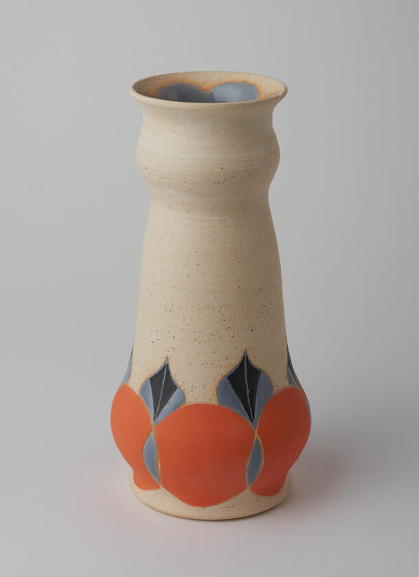 Ceramic vase with carving and orange circle design along bottom edge