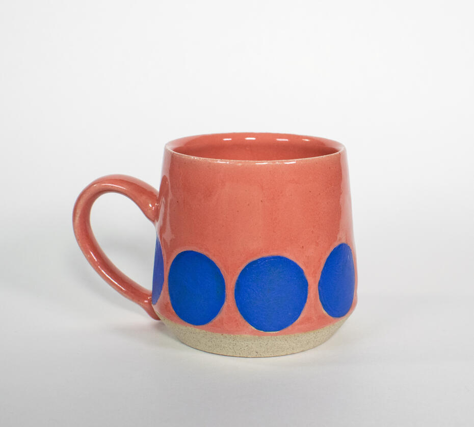 Pink ceramic mug with blue circles along bottom exterior.